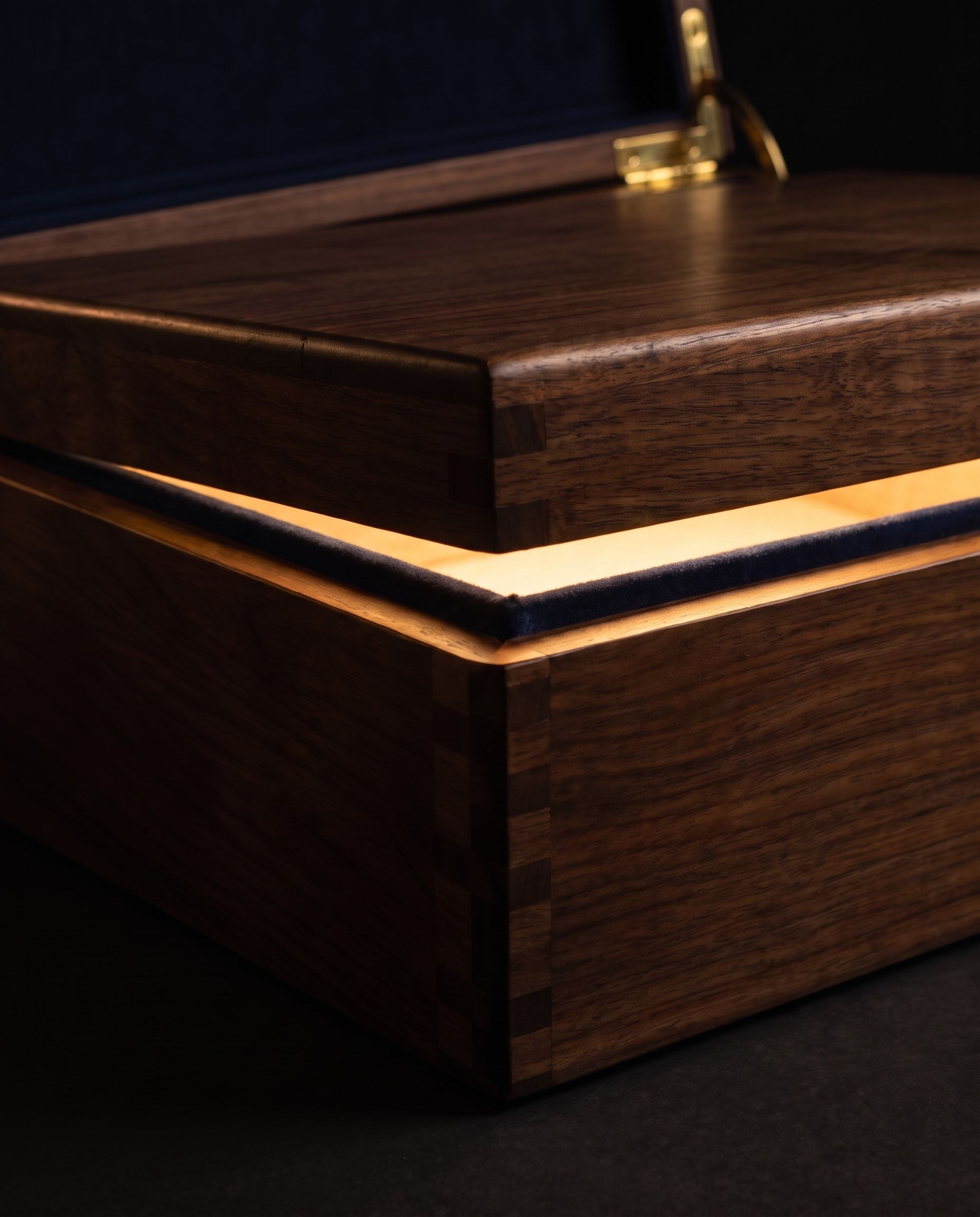 The walnut chest with its lid raised a few centimetres, warm light falling across the navy velvet edge